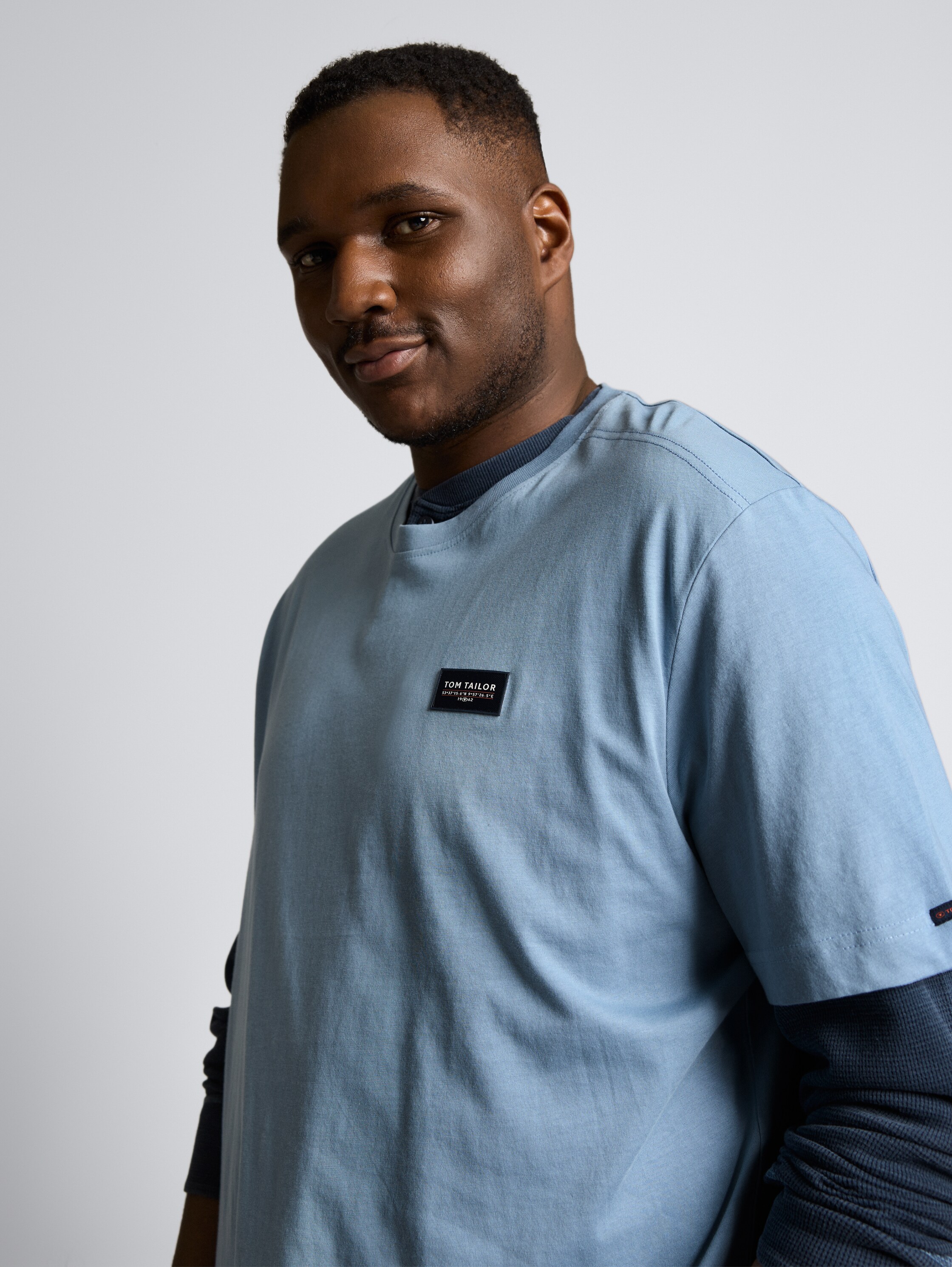 Plus Size - T-Shirt aus Baumwolle mit Logo-Badge - mountain spring blue - Detail-Model-Ansicht